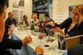 Blonde woman pouring red wine from the bottle to the glass of customer