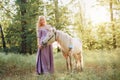 Woman in purple dress hugging white unicorn horse. Dreams come true. Fairy tale Royalty Free Stock Photo