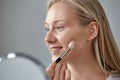 Blonde woman puts blush on her face with a cosmetic brush Royalty Free Stock Photo