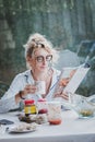 Blonde woman reading a magazine at breakfast time. Royalty Free Stock Photo