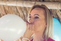 Blonde woman blowing white balloon