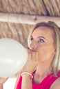 Blonde woman blowing white balloon
