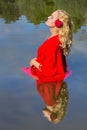 Blonde woman in red stands in natural water