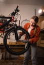 Blonde woman repairing her bike. Lady fixing her bicycle while working on home garage. Bicycle Mechanic. Royalty Free Stock Photo