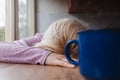 Blonde woman resting her head on a kitchen table cup of coffee in front of her Royalty Free Stock Photo