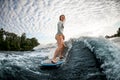 Blonde woman rides down the wave on surfboard against cloudy sky background Royalty Free Stock Photo