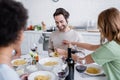 blonde woman serving pasta to cheerful