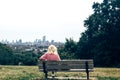 Blonde woman sitting alone on a bench