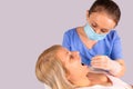 Blonde woman sitting in a chair in the dentist office and woman stomatologist in a medical mask and protective gloves