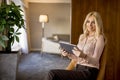 Blonde woman sitting on chair and using digital tablet Royalty Free Stock Photo