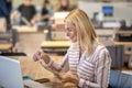 Blonde woman sitting at laptop, opening envelope