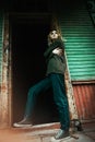 A blonde woman stands at the dark doorway of an old wooden abandoned house. A lonely teenager. Youth vibe Royalty Free Stock Photo