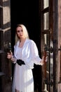 Blonde woman stands in the old wooden doorway. The old wooden door. Young woman modern portrait Royalty Free Stock Photo