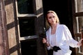 Blonde woman stands in the old wooden doorway. The old wooden door. Young woman modern portrait Royalty Free Stock Photo