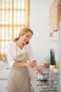 Blonde woman stirring something in a saucepan and talking on the phone Royalty Free Stock Photo