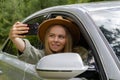 Blonde woman stoped car on road to take a selfie photo. Young tourist explore local travel making candid real moments