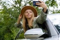 Blonde woman stoped car on road to take a selfie photo. Young tourist explore local travel making candid real moments Royalty Free Stock Photo