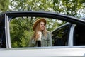 Blonde woman stoped on road next to car and drink coffee or tea from reusable mug. Refuse reuse recycle zero waste