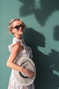 blonde woman on summer attire projecting shadow on a green wall