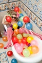 Blonde woman with sunglasses playing in her bath tube with bright colored balloons. Sensual girl with white red striped stockings Royalty Free Stock Photo