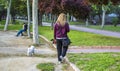 Blonde woman take her dog for a walk with a dog leash on the park