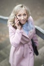 Spring portrait- A blonde woman talking on a mobile phone on the street. Walk around town.