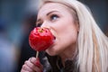 Blonde woman tasting a red apple candy Royalty Free Stock Photo