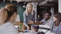 Blonde woman team leader giving direction to mixed race team of young guys. Creative business meeting at modern office. Royalty Free Stock Photo