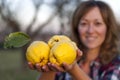 Blonde woman with three quinces in her hand.