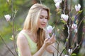 Blonde woman touching magnolia tree.