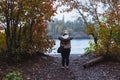 Blonde woman tourist takes photos of Lake Superior along a trail near the beach in autumn Royalty Free Stock Photo