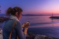 Blonde woman using a mobile phone in front of a harbor during sunset Royalty Free Stock Photo