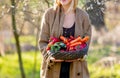 Blonde woman with vegetables in basket in blooming garden