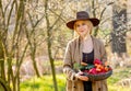 Blonde woman with vegetables in basket in blooming garden