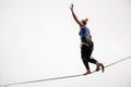 Blonde woman walking on a slackline against the grey sky