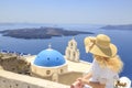 Blonde woman watching view of Santorini near three bells of Fira church in Fira, Santorini, Greece Royalty Free Stock Photo