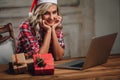 Blonde woman wearing santa hat, working with laptop Royalty Free Stock Photo