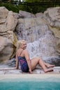 Blonde woman wearing two piece tankini poses at an outdoor pool area of a luxury resort