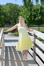 Blonde woman in yellow sundress poses on bridge