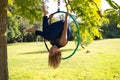 Blonde woman and young gymnast acrobat athlete performing aerial exercise on air ring outdoors in park. Lithe woman in blue