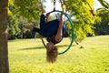 Blonde woman and young gymnast acrobat athlete performing aerial exercise on air ring outdoors in park. Lithe woman in blue