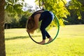 Blonde woman and young gymnast acrobat athlete performing aerial exercise on air ring outdoors in park. Lithe woman in blue