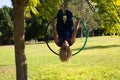 Blonde woman and young gymnast acrobat athlete performing aerial exercise on air ring outdoors in park. Lithe woman in blue