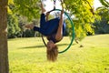 Blonde woman and young gymnast acrobat athlete performing aerial exercise on air ring outdoors in park. Lithe woman in blue