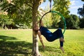 Blonde woman and young gymnast acrobat athlete performing aerial exercise on air ring outdoors in park. Lithe woman in blue