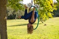 Blonde woman and young gymnast acrobat athlete performing aerial exercise on air ring outdoors in park. Lithe woman in blue