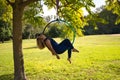 Blonde woman and young gymnast acrobat athlete performing aerial exercise on air ring outdoors in park. Lithe woman in blue