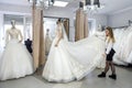 Blonde woman helping bride in wedding shop