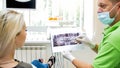 Young blonde woman looking at x-ray image of her teth in dentist office