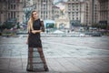 Blonde wooman dreesed in black dress in the city. Rainy day. Royalty Free Stock Photo